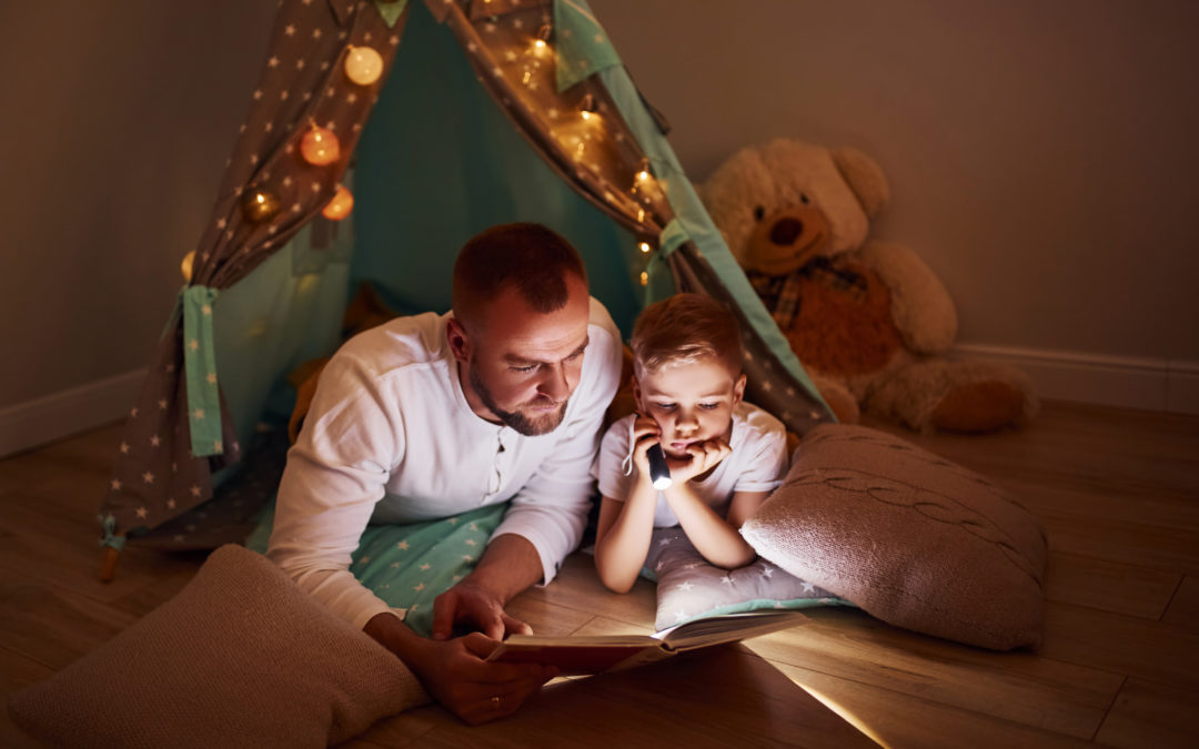 Father and son reading in a cozy tent.